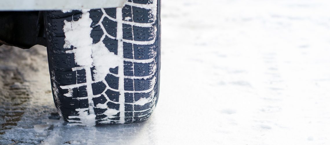 Car tires on winter road covered with snow. Vehicle on snowy alley in the morning at snowfall